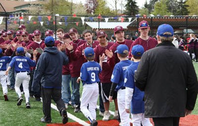 Members of the Mercer Island High School baseball team slap hands with a Mercer Island Little League team during the Opening Day ceremony at the South Mercer Playfields on Saturday