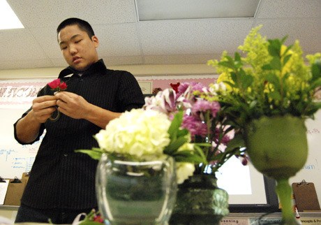 James Suh works on creating a boutonniere during his culminating project presentation about flower arrangements.