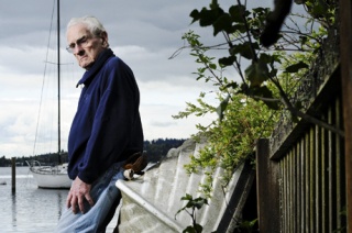 Island native Hu Riley leans against a boat on his lakeside property in the North Mercer neighborhood. A large group of North Mercer residents have supported naming the body of water between Luther Burbank Park and the Roanoke Inn ‘Riley Cove’ in honor of the Island citizen