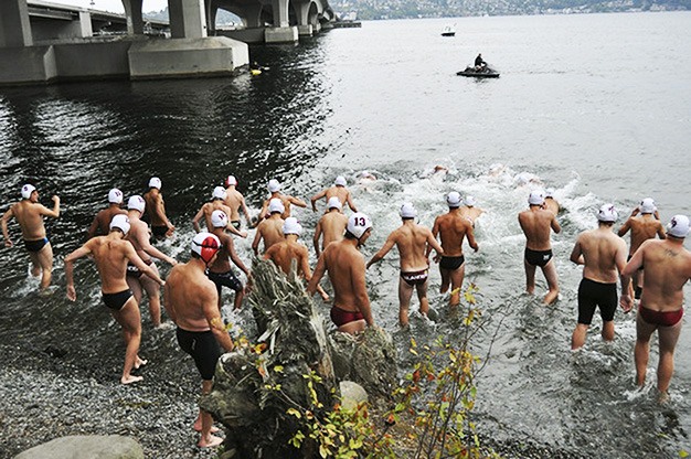 Members of the Mercer Island High School boys water polo team head into Lake Washington to swim across the lake and return to the Island by running across I-90. It is a team tradition.