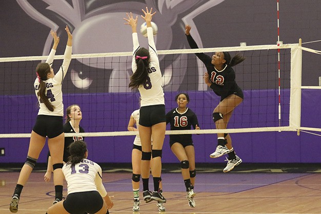 Mercer Island's Jemma Yeadon (12) fires a spike at Lake Washington middle blockers Nicole Tisdel (24) and Lexi Lum (8) Thursday night at Lake Washington High School. The Islanders beat the Kangs 15-25