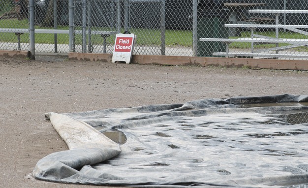 Tarps cover part of the infield of the baseball field at Island Crest Park while the field is closed for being too wet. The City is applying for a grant which would convert the field to turf.