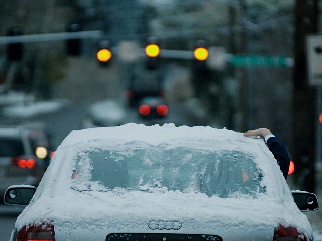 A passenger grabs a handful of snow from the car roof along SE 40th Street and Island Crest Way on Mercer Island on Monday.