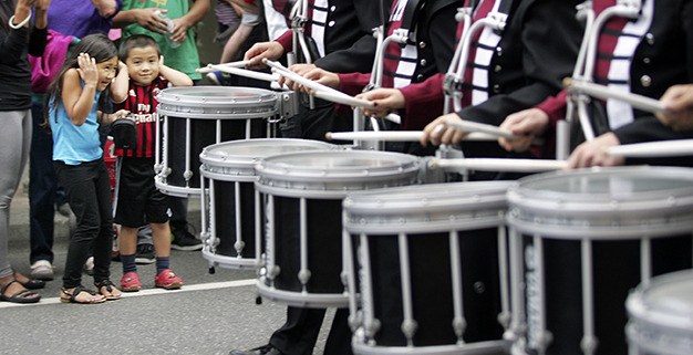 Children cover their ears as the percussion section of the Mercer Island High School marching band passes in Friday's homecoming parade.