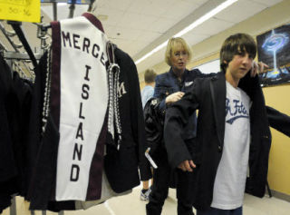 Freshman trumpet player Joseph Shanks gets help with finding a marching band uniform that fits from parent volunteer Eileen Concannon at Mercer Island High School. The band will march at the Islander football team’s home opener this Friday.