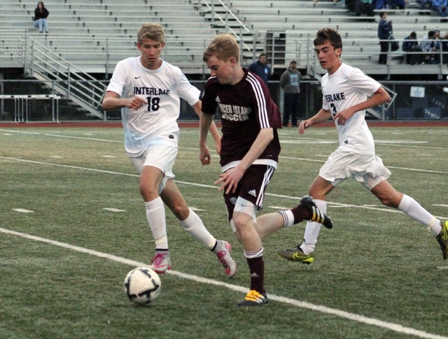 Mercer Island’s Hunter Bauman (center) weaves through Interlake defenders Owen Gortner (18) and Noah Parsons (3) Wednesday night at Interlake High School. The Islanders beat the Saints 3-0 (Joe Livarchik/staff photo).