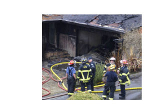 Officers clean up after a fire in the 3000 block of 68th Avenue S.E. on Feb. 15. Firefighters say the fire was started by ashes stored in the garage.