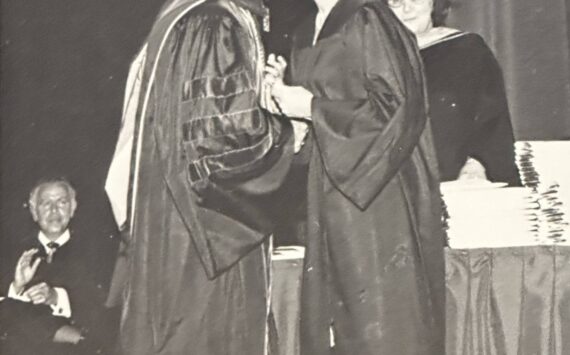 President David McKenna kisses his wife after presenting her her college diploma (June 1974) Greg’s father applauds in the lower left hand corner. Courtesy photo
