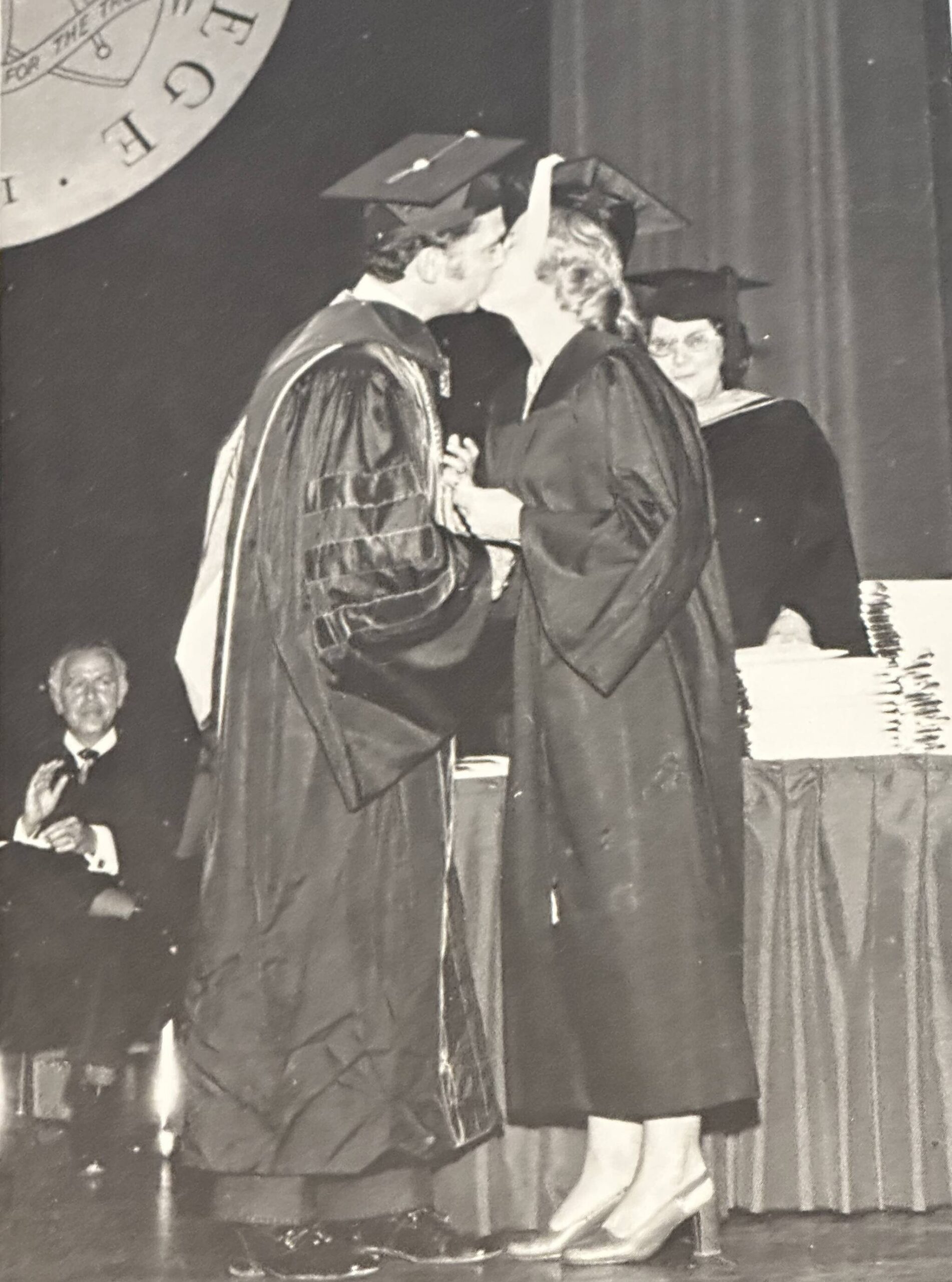 President David McKenna kisses his wife after presenting her her college diploma (June 1974) Greg’s father applauds in the lower left hand corner. Courtesy photo