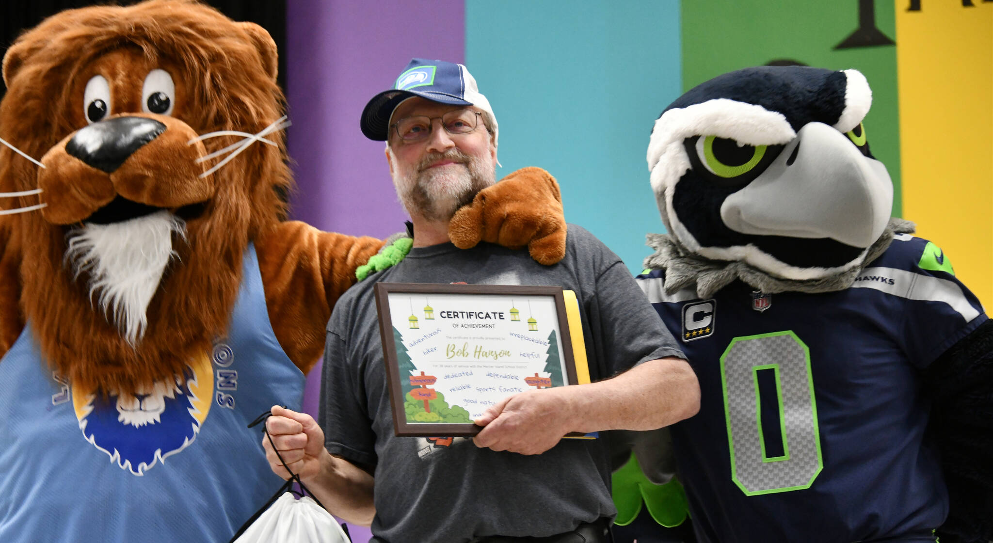 Seahawks mascot Blitz and Leo the Lion (Mercer Island School District Superintendent Dr. Fred Rundle) flank Lakeridge Elementary School head custodian Bob Hanson during a school assembly on June 11. The school celebrated Hanson, who is retiring after 35 years at Lakeridge and 38 overall with the district. Andy Nystrom/ staff photo