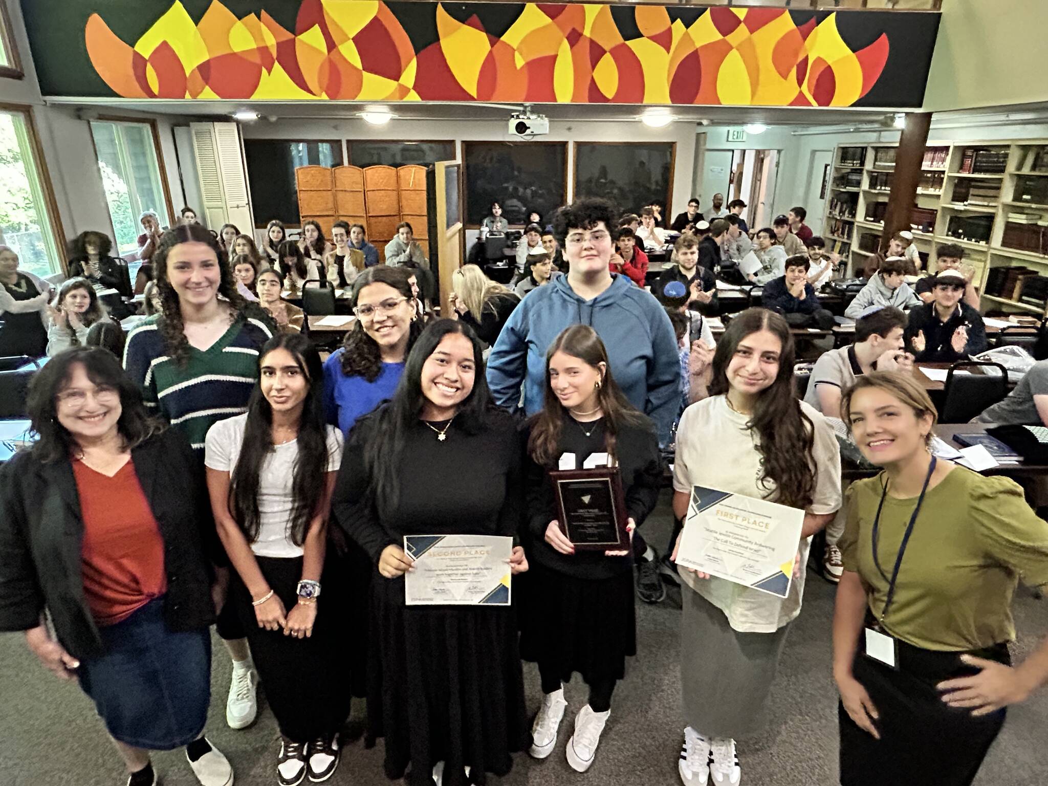 Joelle Keene, president and executive director of the Jewish Scholastic Press Association, visited Northwest Yeshiva High School (NYHS) on Aug. 29 to present a pair of awards to local students in the Emily Alhadeff-taught journalism department. Students received awards for their feature stories in the high school newspaper, The Mane Idea. Jenna Kaufthal, a recent NYHS graduate, won first place in a tie with Shalhevet High School in the category of “News and feature reporting on current events involving Israel.” The article, titled “Answering the Call to Defend Israel,” was featured by The Mane Idea in December of 2023. Elianna Rothstein, now an NYHS senior, won second place in the category of “News or feature reporting on interreligious or intercultural activism or events” for her December 2023 piece titled, “Mercer Island Muslim and Jewish leaders work together against hate.” Photo courtesy of Zelle Rettman