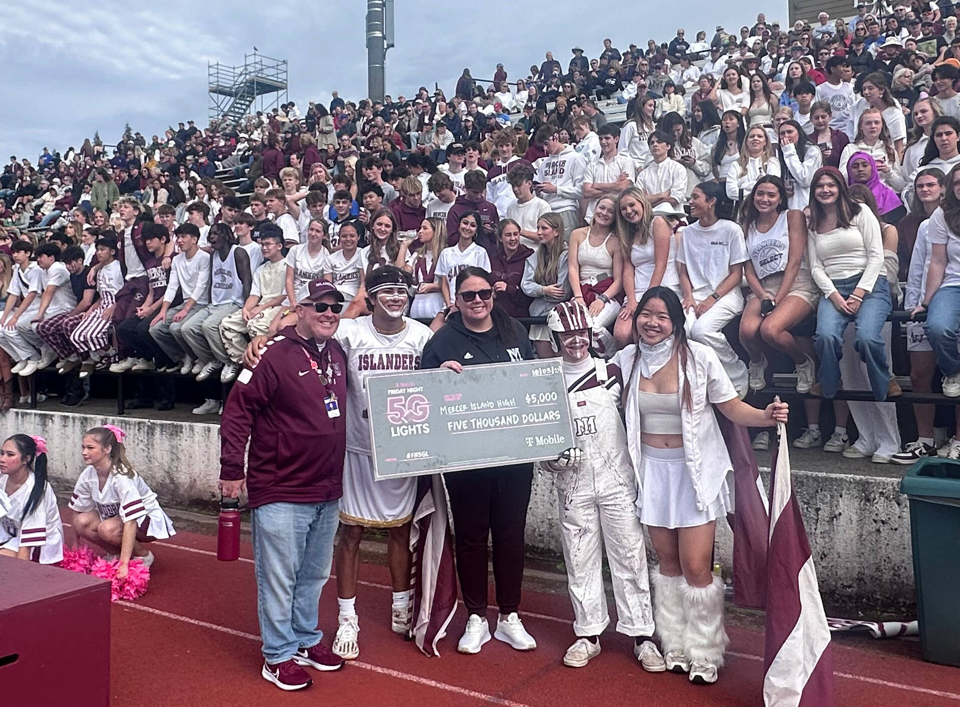 Mercer Island High School Principal Nick Wold and Athletic Director Lindsey Blaine celebrate with students during the Oct. 5 Homecoming football game at Islander Stadium on being named a T-Mobile Friday Night 5G Lights program $5K winner. The Islanders beat Newport, 31-10. Islander fans lent overwhelming support and school spirit to get the T-Mobile win. Local T-Mobile representative Jay Lee and staff members presented a $5,000 check to Blaine at halftime. The school’s next goal is to be named a top 16 finalist. Island resident Rob Wolf apprised the school about the promotion. Photo courtesy of the Mercer Island School District