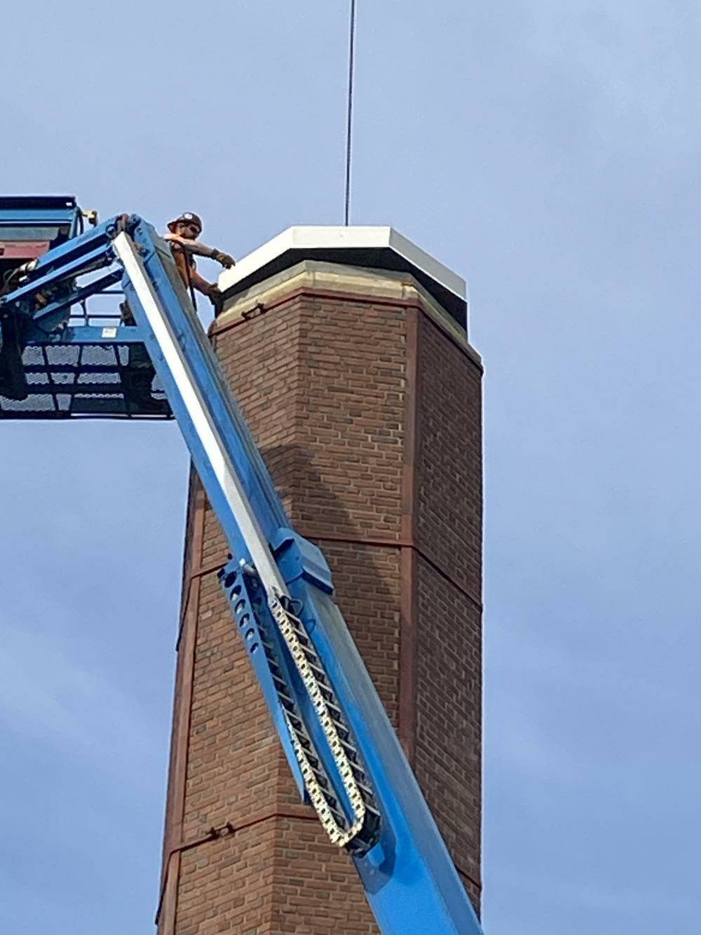 A worker positions a steel roof cap on the chimney of the Luther Burbank Park boiler building. Photo courtesy of the city of Mercer Island